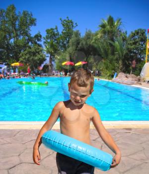Serious kid stands near the pool in the spa resort