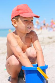 Cute little boy with a bucket on the beach by the sea