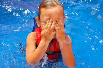 Kid in the swimming pool  covered his face with his hands