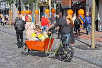 DORDRECHT, THE NETHERLANDS - SEPTEMBER 28:Young parents carry children in the bicycle stroller by celebratory street on September 28, 2013 in Dordrecht, Netherlands 