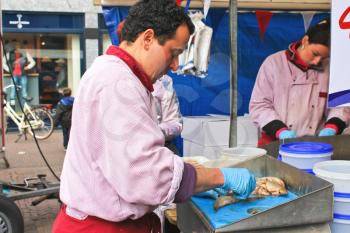 DELFT, THE NETHERLANDS - APRIL 7, 2012 : Workers cut up fish for sale at a market  in Delft, Netherlands