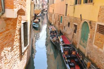 Gondolas and boats in a narrow canal in Venice, Italy