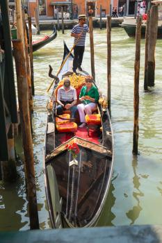 VENICE, ITALY - MAY 06, 2014: Gondolier sails with tourists sitting in a gondola, Venice, Italy