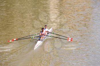 FLORENCE, ITALY - MAY 08, 2014: Two athletes in academic rowing training on the river Arno. 