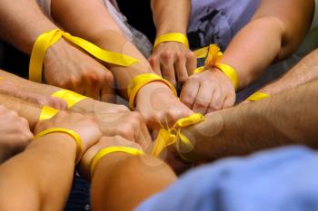 Hands with yellow ribbons together. The concept of the unity of sport