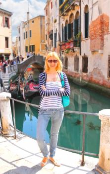 Attractive girl on the waterfront of a narrow canal in Venice, Italy
