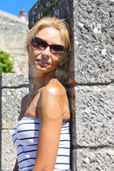 Attractive girl in sunglasses near the fortress wall