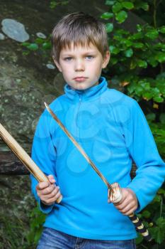 Serious kid with a wooden sword on stone