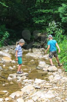 Two kids playing near a mountain stream