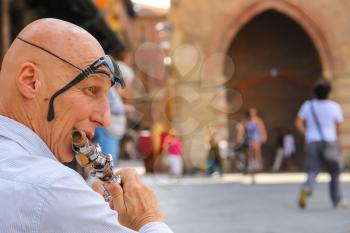 Bologna, Italy - August 18, 2014: Street musician playing the flute on Piazza Maggiore in Bologna. Italy