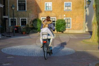 Meerkerk, municipality Zederik, Netherlands - April 13, 2015: The woman and little girl riding a bicycle in the Dutch city Meerkerk, Netherlands