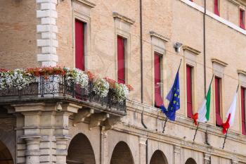 Facade of Rimini City Hall with flags and flowers on Cavour square in Rimini, Italy