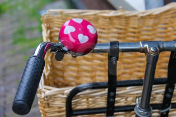 Pink bicycle bell with white hearts on handlebars