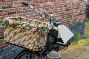 Bicycle with flower decorated wicker basket near the brick wall