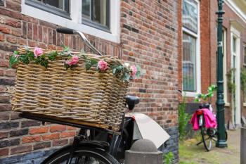 Bicycle with flower decorated wicker basket near the brick house