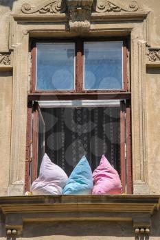 Opened window with three pillows in old house