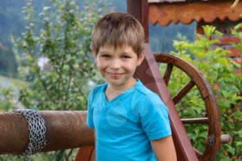 Smiling boy in front of old style wooden well