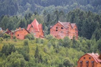 Modern cottages on slopes of forested mountains. Carpathians, Ukraine