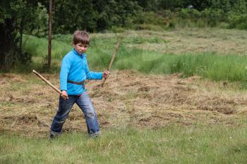 Boy with wooden sword in summer forest park