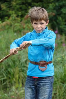 Boy with wooden sword in summer forest park