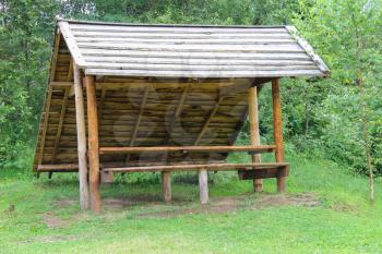 Old style wooden canopy with bench in forest park