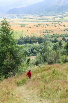Boy walks picturesque hills of Carpathians. Schodnica, Ukraine
