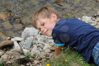 Boy lies near mountain river in Carpathians, Ukraine