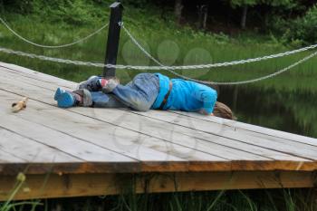 Boy lies on wooden bridge by the lake