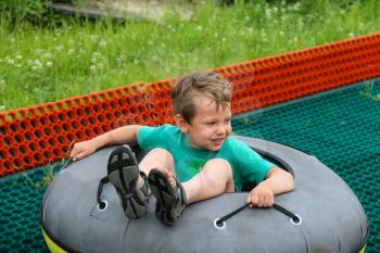 Smiling boy slides down in inflatable ring