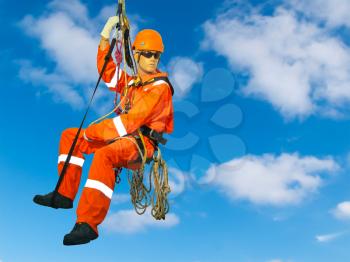 Mannequin in overalls steeplejack on cloudy sky background