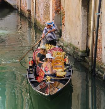Venice, Italy - August 13, 2016: Tourists in gondola on canal of Venice