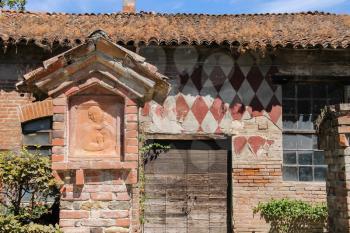 Old building with the icon of the Virgin on the wall. Grazzano Visconti castle, Italy