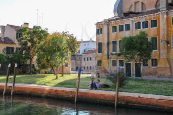 Venice, Italy - August 13, 2016: Tourists resting in small park near water