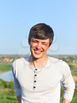 Summer portrait of a handsome young man laughing. Soft evening sunlight