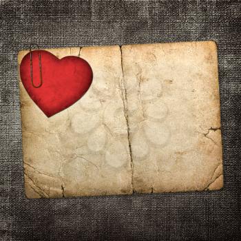 old paperboard card with red paper heart on a dark fabric background 