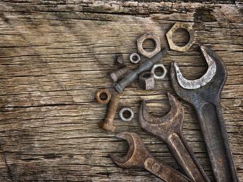 Old wrenches on the nuts and bolts on a wooden grungy background