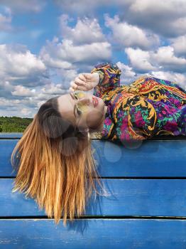 Girl with her hair lies on a fence against the sky