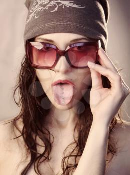 Freak-girl in sunglasses shows her tongue with pierced