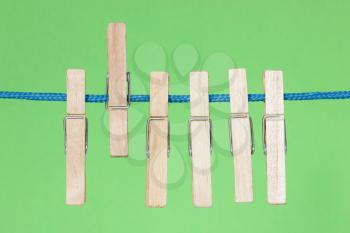 Wooden clothes pegs hang on the green background