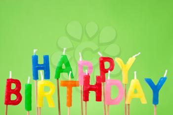 colorful candles forming the sentence happy birthday on green background