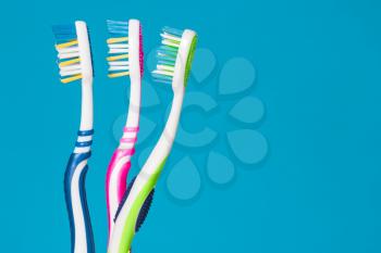 Three tooth brushes on the blue background 