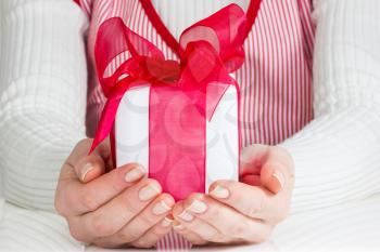 Woman showing white gift box with big red bow