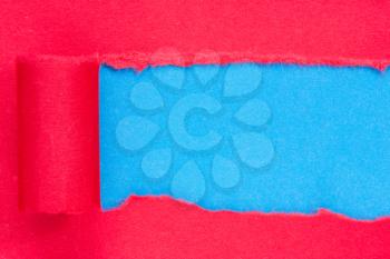 Red paper torn to reveal blue panel ideal for copy space	
