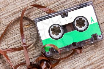 Retro audio cassette  with pulled out tape on the wood background