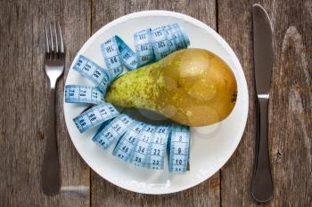 Royalty Free Photo of a Pear and a Measuring Tape on a Plate