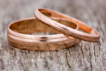 Pair of golden wedding rings on a wooden background