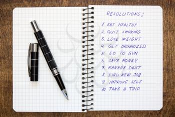 Spiral notebook with list of resolutions on the wooden table