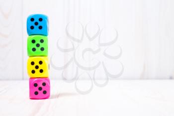 Colorful dice stacked on the white wooden surface