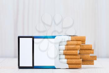 Open full pack of cigarettes on white wood background