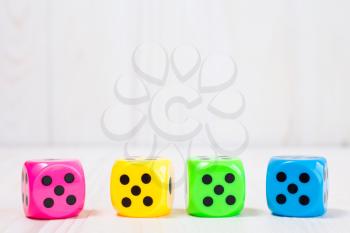 Four color dice on the white wooden background